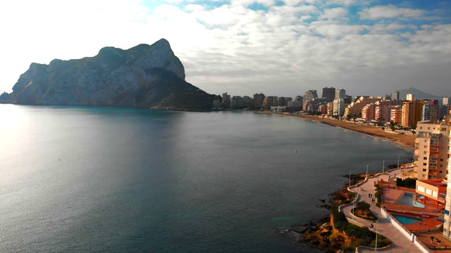 西班牙阿利坎特卡尔佩市日出时的鸟瞰图。La Fossa海滩在前景和de Ifach Penon岩石在背景。视频素材