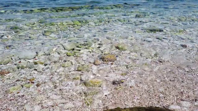 小海浪在沙滩上翻滚，在阳光下撞击岩石的特写。科孚岛碧波荡漾，海水清澈视频下载