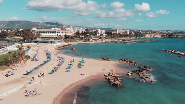 沙滩鸟瞰图。无人机拍摄的旅游海滩。无人机飞过蓝色海水的海岸线。有酒店和海滩的旅游区。游客躺在海滩上。女人和男人在晒日光浴视频素材