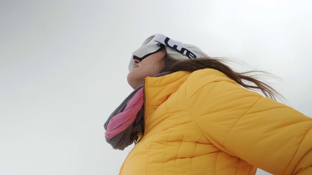 一个年轻女人的特写肖像把她的滑雪眼镜在雪上在一个滑雪胜地。赏冬山。准备在白雪皑皑的山上滑雪。下坡滑雪。视频素材