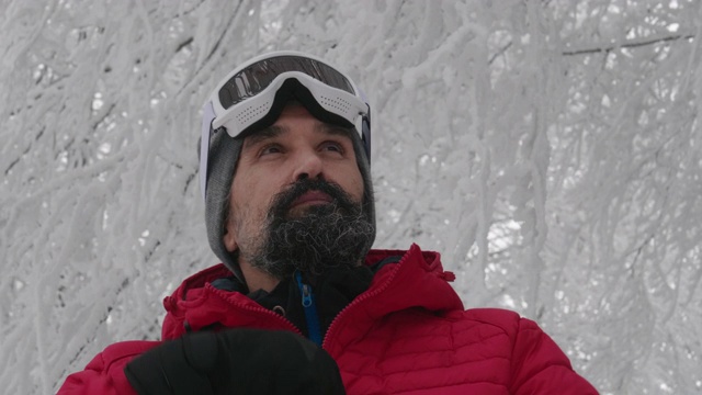 一个成熟的男人在滑雪场雪地上戴上滑雪眼镜的特写肖像。赏冬山。准备在白雪皑皑的山上滑雪。下坡滑雪。视频素材