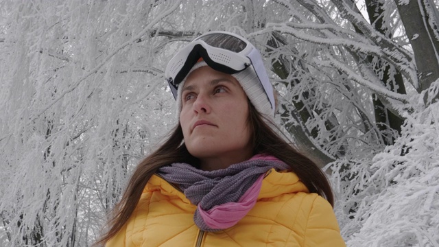 一个年轻女人的特写肖像把她的滑雪眼镜在雪上在一个滑雪胜地。赏冬山。准备在白雪皑皑的山上滑雪。下坡滑雪。视频素材