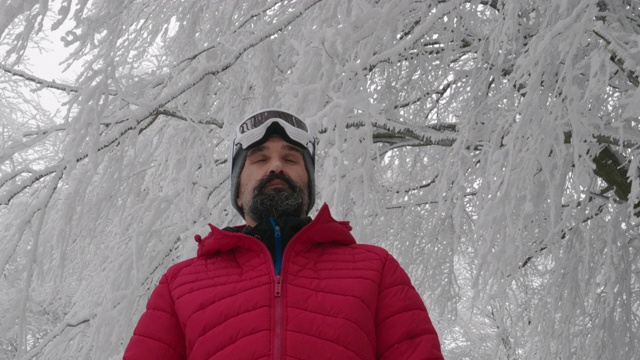 一个成熟的男人在滑雪场雪地上戴上滑雪眼镜的特写肖像。赏冬山。准备在白雪皑皑的山上滑雪。下坡滑雪。视频素材