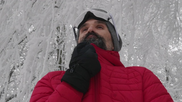 一个成熟的男人在滑雪场雪地上戴上滑雪眼镜的特写肖像。赏冬山。准备在白雪皑皑的山上滑雪。下坡滑雪。视频素材