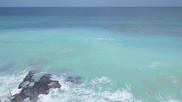 从悬崖上看，美丽的海滩上有岩石和生动的蓝色海水视频素材