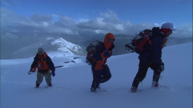 登山运动员徒步穿越山顶的积雪。视频素材