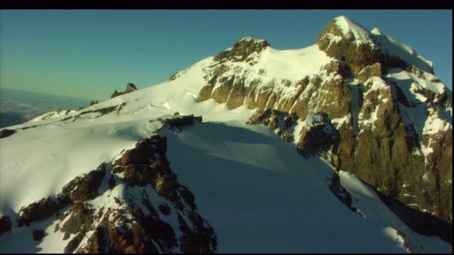 一架直升机在白雪皑皑的山顶上空盘旋。视频素材