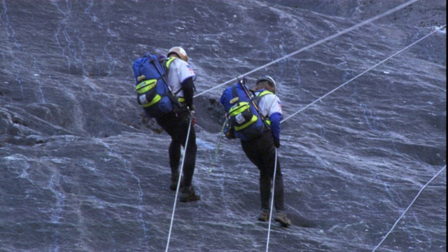 登山队从光滑的岩石表面攀爬而下。视频素材