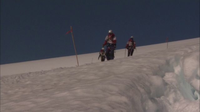 登山者沿着积雪的斜坡下山。视频素材