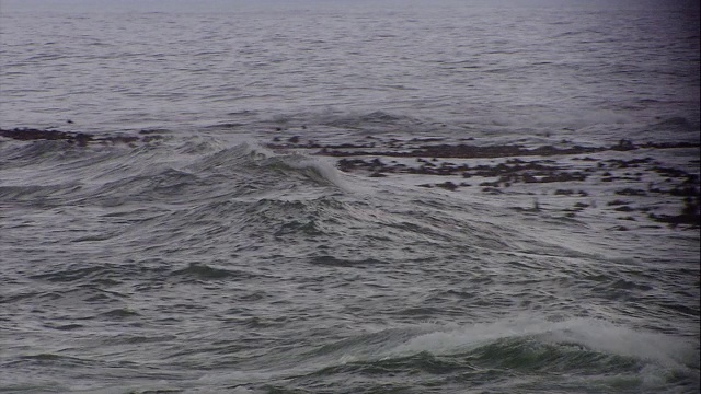 海浪滚到岩石沙滩上。视频素材