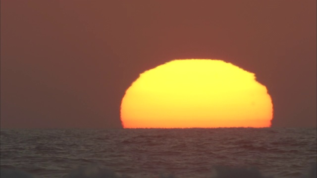 融化的太阳在汹涌的波浪中下沉。视频素材