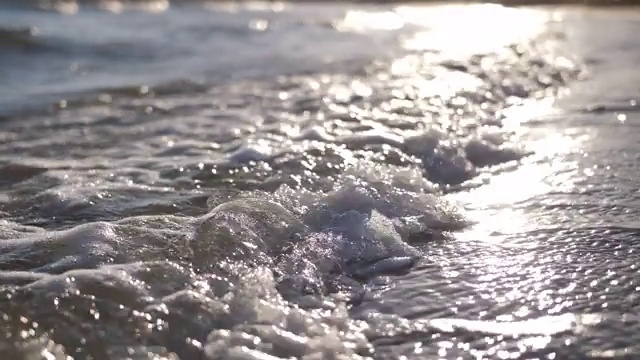 西班牙日落时海滩上的浪花，浪花带着泡沫的慢动作视频素材