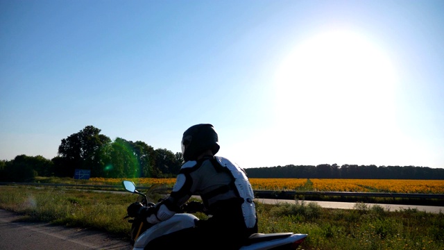 戴头盔的男子在高速公路上骑摩托车。摩托车手骑着摩托车与风景优美的自然景观赛跑。穿着防护装备的家伙享受旅行。冒险或自由的概念。侧视图视频素材