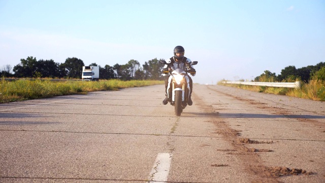 戴头盔的男子在高速公路上驾驶强大的运动摩托车。摩托车在乡间柏油路上超速行驶。穿着防护装备享受速度的家伙。自由的概念。慢动作视频素材