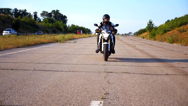 戴头盔的男子在高速公路上驾驶强大的运动摩托车。摩托车在乡间柏油路上超速行驶。穿着防护装备享受速度的家伙。自由的概念。慢动作视频素材