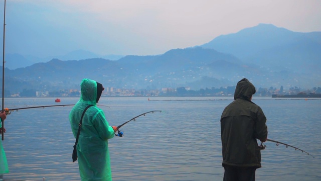 许多渔民在海里捕鱼。在山峦的背景下，是一道美丽的风景。视频素材