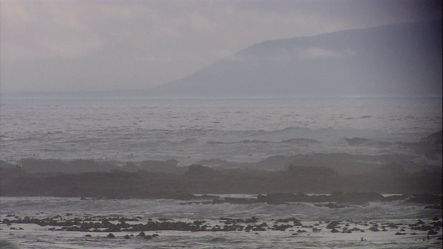 在南非开普敦，雾笼罩着海浪，海浪冲刷着崎岖的海岸。视频素材