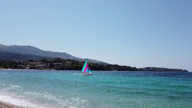 风帆冲浪和双体船在爱奥尼亚海科孚风帆冲浪海浪，休闲水上运动的观点从海滩视频下载