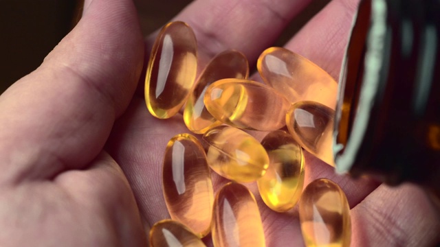 男子从药瓶中将Omega - 3维生素凝胶胶囊倒进手上，特写视频素材