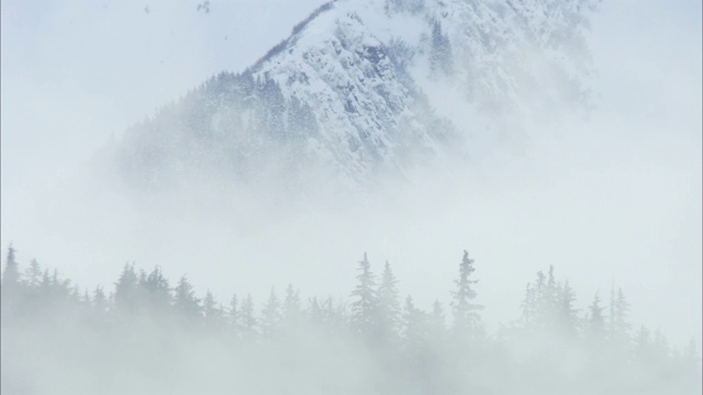 雪云漂浮在白雪覆盖、崎岖的山脚下。视频素材