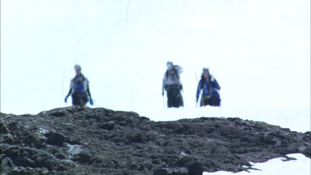 登山者徒步穿越巴塔哥尼亚一个多岩石的雪坡。视频素材