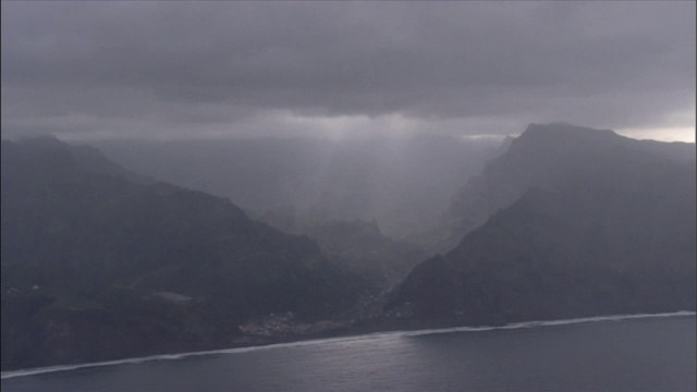 阳光穿透了多山的海岸上空的暴雨云层。视频素材