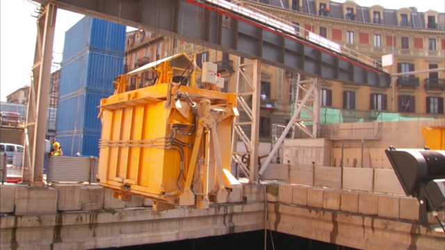 起重机从建筑工地的地基上吊起一个集装箱。视频素材