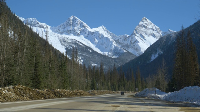 小卡车沿着雪山下的风景优美的公路行驶视频素材