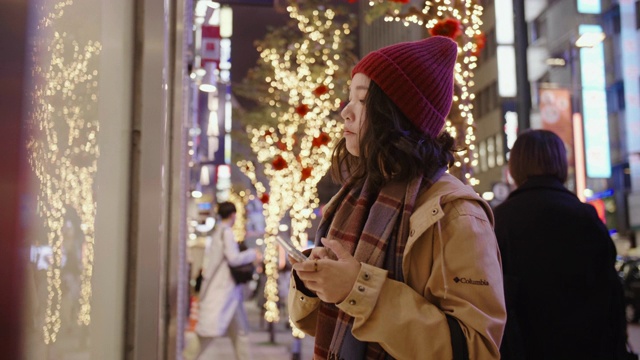 亚洲女孩戴上羊毛帽子和围巾。她在城里的圣诞市场购物。视频素材