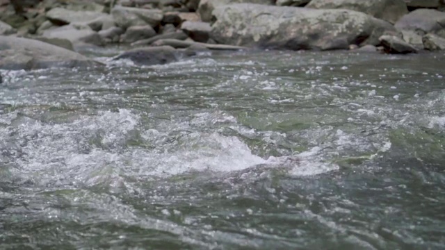 水流缓慢地流过岩石，在落下时有小波浪。视频下载