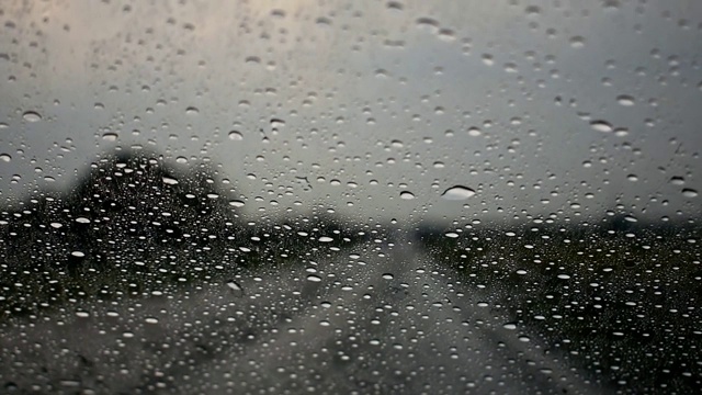 雨水落在汽车的挡风玻璃上。街上下着大雨，晚上行驶的汽车——天气状况危险。视频下载