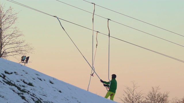 滑雪胜地的缆绳将滑雪者和滑雪板者拉上山。夕阳的天空在背景视频素材