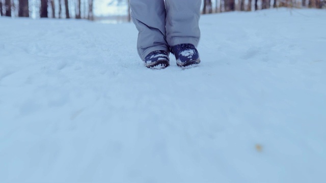 雪地里有脚步声，穿着冬靴的脚踩在雪地上。特写镜头。视频素材