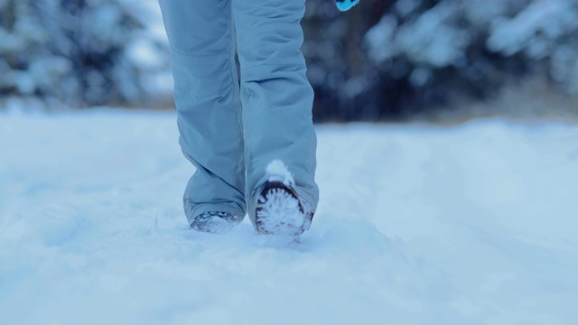 穿着冬天鞋子的脚把路面踩在雪地里。走在森林里松软的雪地里。特写镜头。视频素材