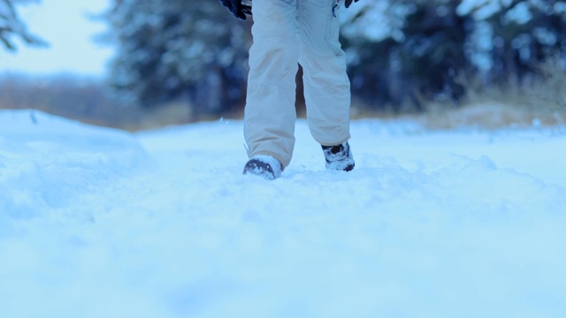 男脚走在明净的雪地里，冬天走着。一个穿着冬靴的人走在森林里铺满雪的路上。特写镜头。视频素材