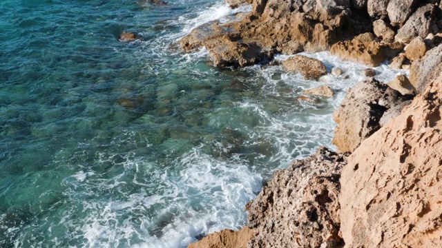 海浪拍打着岩石。巨浪撞击悬崖。清澈湛蓝的海水和布满岩石的海岸。海岸边的大海浪。海浪拍打着岩石。视频素材