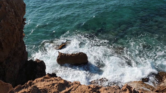 海浪撞击悬崖的顶视图。清澈湛蓝的海水撞击着岩石。俯视图的海洋景观。悬崖的边缘俯瞰视频素材