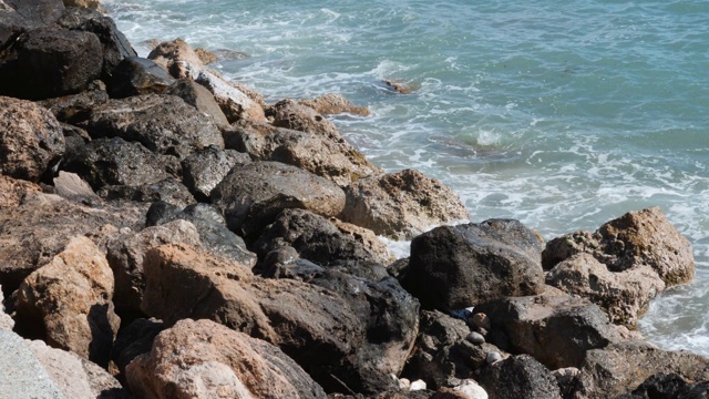 近距离观看石头与大海浪。海浪冲击岩石海岸。蔚蓝的海水冲击着岩石的海岸。浪花溅起并产生泡沫。慢动作视频素材