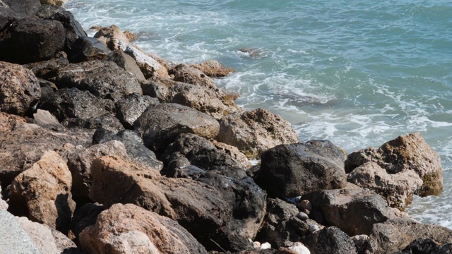 近距离观看石头与大海浪。海浪冲击岩石海岸。蔚蓝的海水冲击着岩石的海岸。浪花溅起并产生泡沫视频素材