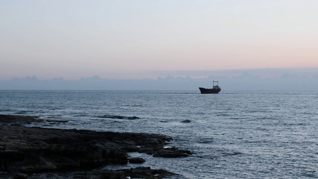 生锈的旧船搁浅在多岩石的海岸上。美丽的海景与大货船的背景。一艘货船在海上搁浅。从多岩石的海岸看海景。视频素材