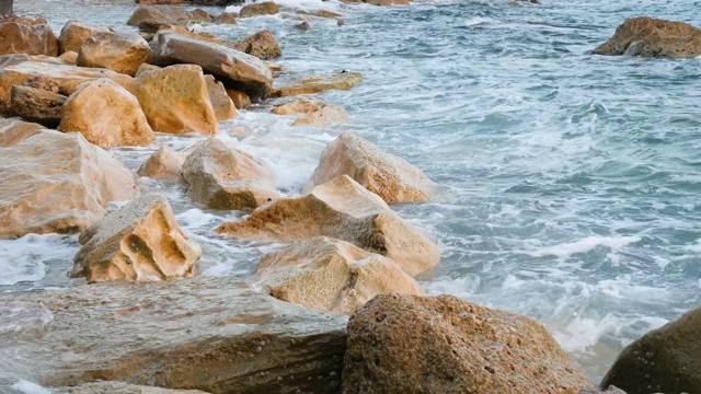 巨浪撞击岩石，近景。海浪在多岩石的海岸溅起水花并产生泡沫视频素材