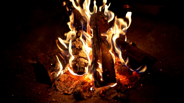 火焰在黑夜中燃烧。木头在篝火中燃烧。余烬因温度高而呈红色。慢动作特写镜头视频素材