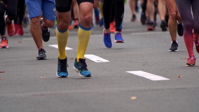 参加城市马拉松比赛的人群。男人和女人穿着运动服。身体的下部。腿部肌肉紧张和放松。慢动作镜头视频素材