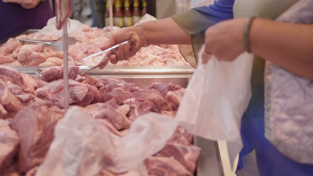 女人选择在超市买鸡肉、猪肉。视频素材