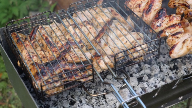 在木炭烤架上准备炸鸡的男子。厨师在户外烹饪烤肉。有人在烤架上翻煤视频素材