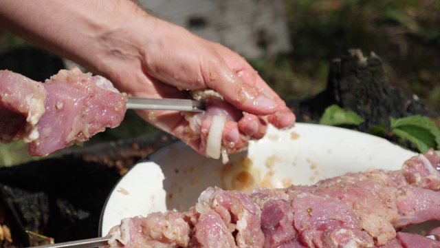 男人用叉子刺肉。厨师在木炭烤架上烹饪肉类。准备烧烤的肉。烹饪概念。户外度假视频素材