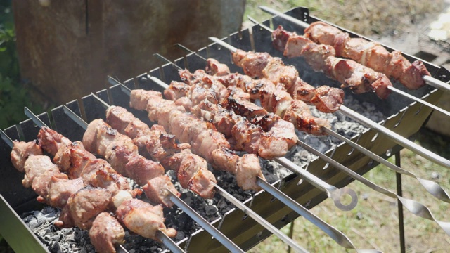 厨师用烤架煎肉。男人把肉串起来。户外烧烤。烹制油炸肉类的过程视频素材