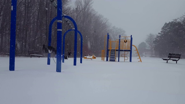 冬天下雪时的儿童乐园。操场上白天下雪，地上有雪。视频素材