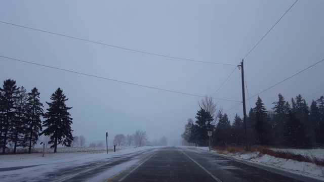 在乡村公路上行驶着冬日暴风雪。司机观点:下雪了，乡下路上下雪了。视频素材