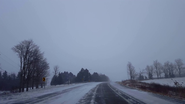 在冬季暴风雪期间沿弯道上坡行驶。司机的观点，下雪的暴风雪下雪的农村道路。视频素材